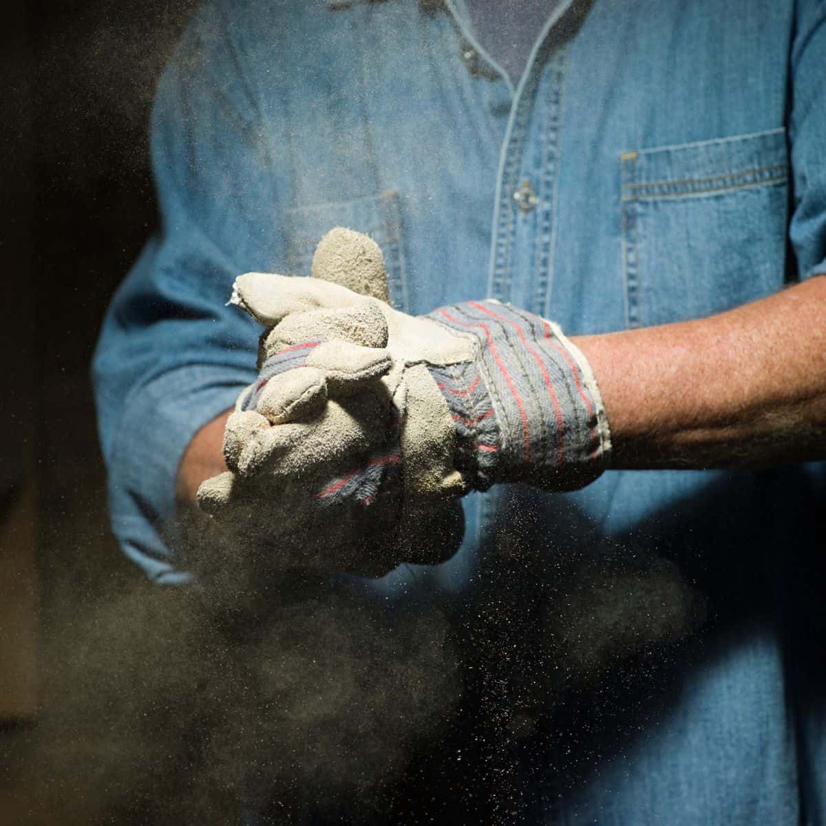 workers gloved hands releasing dust